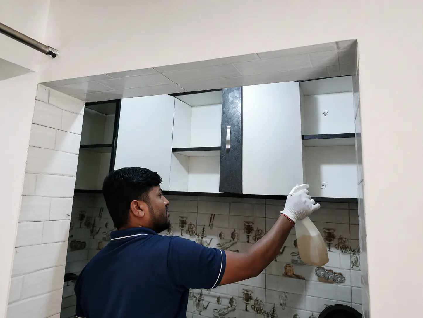 Technician spraying degreaser inside overhead kitchen cabinets